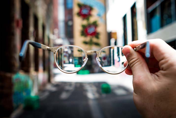 holding-onto-glasses-street-background